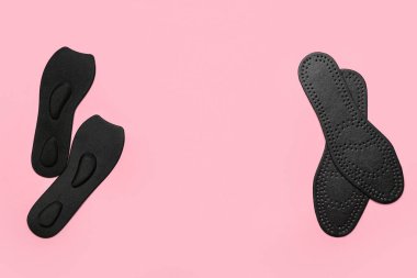 Pembe arkaplanda siyah ortopedik tabanlar