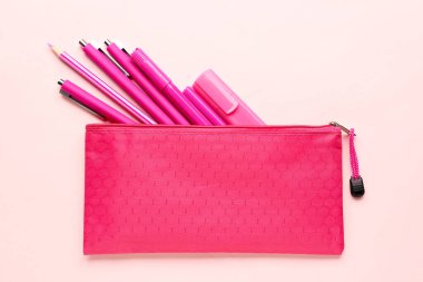 Pembe arka planda farklı okul kırtasiyesine sahip şık bir kalem kutusu.