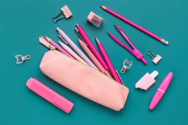 Yeşil arka planda okul kırtasiyesi olan pembe kalem kutusu.
