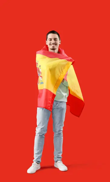 Handsome young man with flag of Spain on red background
