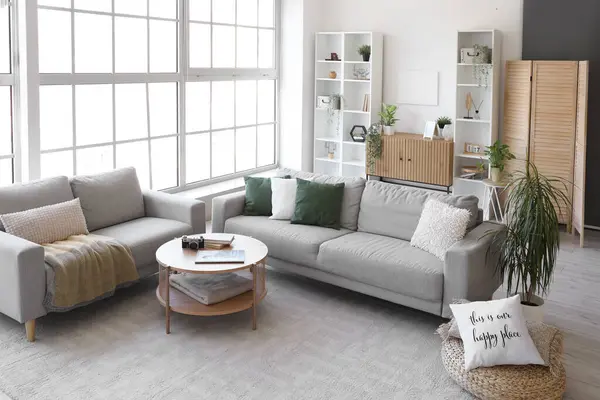 Interior of bright living room with cozy grey sofas and coffee table