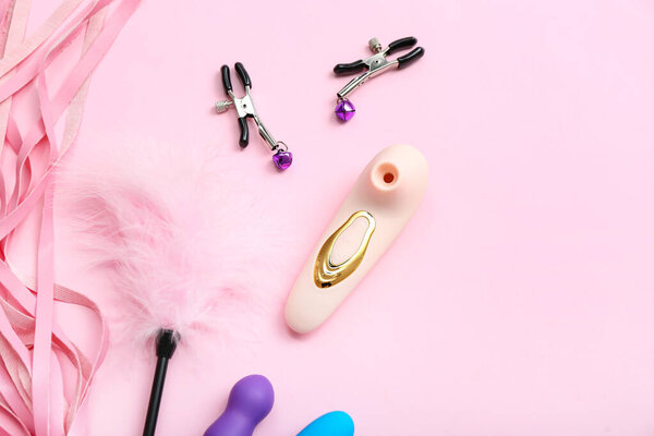 Различные секс-игрушки на розовом фоне, крупный план