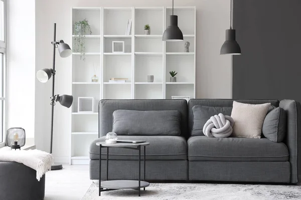 Interior of light living room with cozy grey sofa and coffee table