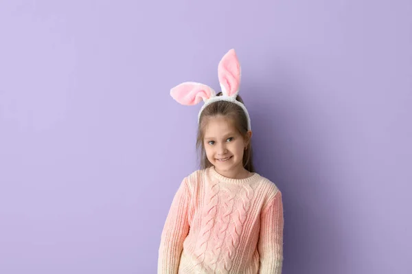 在紫丁香背景上穿着兔子耳朵和针织毛衣的小女孩很可爱 — 图库照片