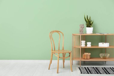 Ahşap sandalye ve renk duvarına yakın dekorlu raf ünitesi.