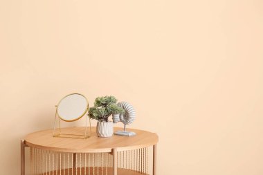 Aynalı ahşap sehpa ve bej duvarın yanındaki dekoratif ağaç.