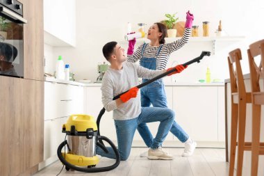 Mutfakta temizlik yaparken şarkı söyleyen mutlu genç çift.