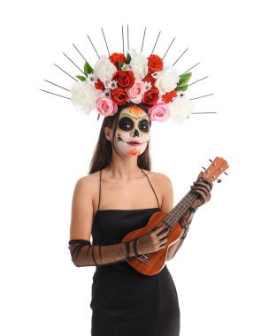 Kafatası boyalı genç bir kadın beyaz arka planda gitar çalıyor. Meksika Ölüler Günü (El Dia de Muertos) kutlamaları