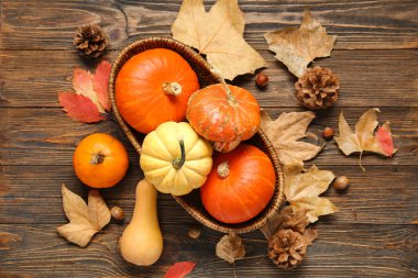 Taze balkabakları ve ahşap arka planda sonbahar yapraklarıyla hasır kase.