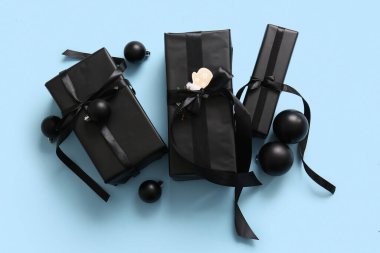 Mavi arka planda siyah hediye kutuları ve Noel topları