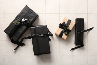 Beyaz fayans zemininde Noel ağacı dalları olan bir sürü hediye kutusu.