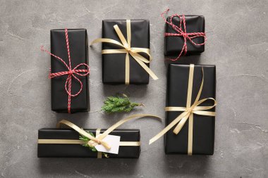 Gri arka planda siyah hediye kutuları ve Noel ağacı dalları