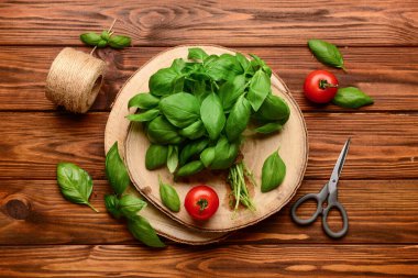 Taze yeşil fesleğen ve ahşap arka planda domatesli tahta.