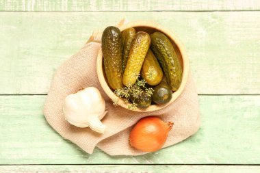 Yeşil ahşap arka planda lezzetli salatalıklı, soğanlı ve sarımsaklı kase.