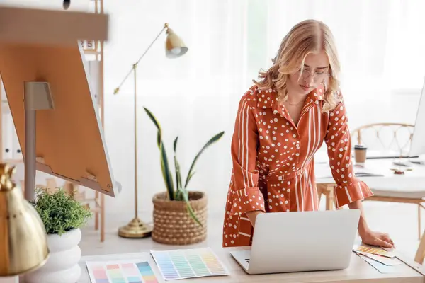 Female interior designer working with laptop at table in office