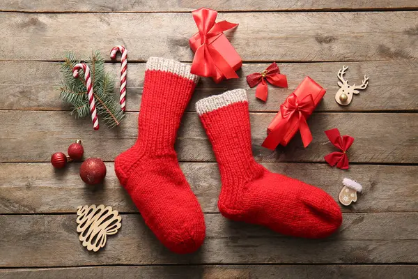 Beautiful Christmas socks with gift boxes and decorations on wooden background