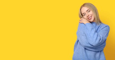 Sarı arka planda kendine sarılan genç bir kadın ve mesaj için yer var.