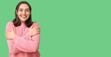 Yeşil arka planda kendine sarılan genç bir kadın ve mesaj için yeri var.