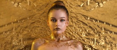 Folyo folyo arka planında parlak makyajlı genç bir kadın.