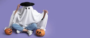 Hayalet kostümü giymiş kişi ve Cadılar Bayramı balkabaklarıyla eflatun arka planda mesaj için yeri olan kişi