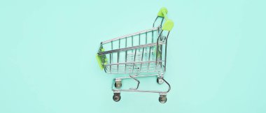 Turkuaz arka planda küçük bir alışveriş arabası. Kara Cuma indirimi