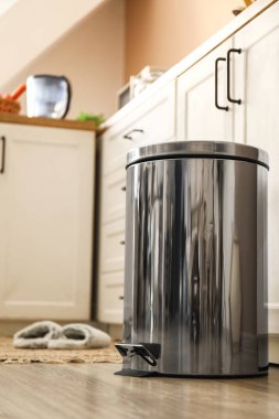 Modern mutfakta yerde metal çöp kutusu var.