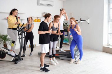 Spor salonunda cep telefonu kullanan bir grup genç.