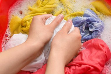 Çamaşırları plastik havuzda su ve köpükle yıkayan kadın, yakın plan.