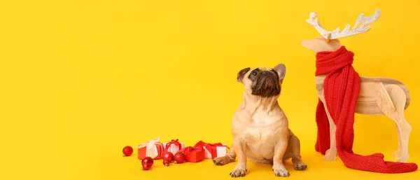 Cute dog with gifts and Christmas decor on yellow background with space for text