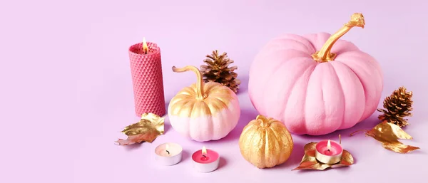 Beautifully painted pumpkins with candles and floral decor on lilac background