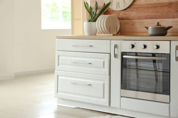 Современная электрическая печь с кастрюлей рядом с деревянной стеной