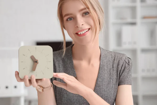 Young businesswoman with clock in office, closeup