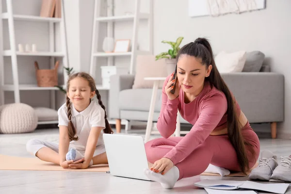 Working mother with her little daughter training at home