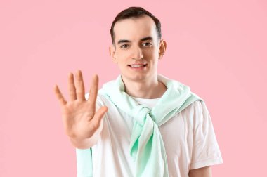 Pembe arka planda beş parmak gösteren genç adam.