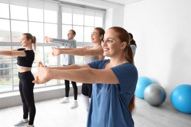 Spor salonunda grupla antrenman yapan genç bir bayan.