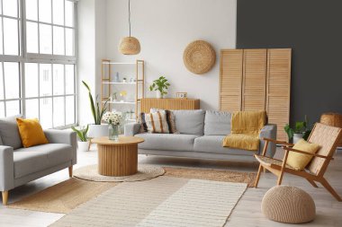 Gri koltukları, tahta koltukları ve kahve masası olan aydınlık oturma odasının içinde.