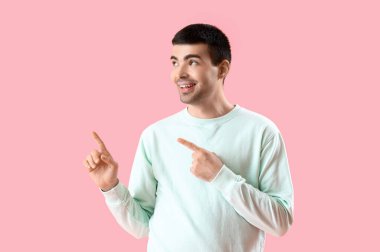 Genç adam pembe arka plandaki bir şeyi işaret ediyor.