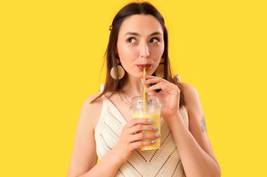 Sarı arka planda smoothie içen genç bayan, yakın plan.