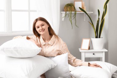 Yumuşak yatağında yastıkları olan güzel genç bir kadının sabahı.