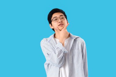 Mavi arka plan üzerinde Düşünceli genç Asyalı adam