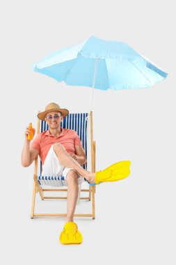 Güneş kremi sürmüş olgun bir adam arka planda iskemlede oturuyor.