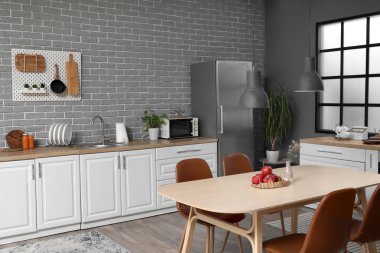 Beyaz tezgahları, yemek masası ve buzdolabı olan modern mutfağın içi.