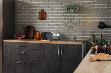 Mutfak tezgahları lavabo, tabak rafı ve çatal bıçak dolu.