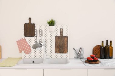 Kesme tahtaları, tahta, lavabo ve çatal bıçakları olan beyaz mutfak tezgahları.