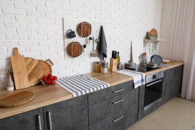 Tahta kesme tahtaları, elektrikli ocak ve ahşap tezgahların olduğu modern mutfağın içi.