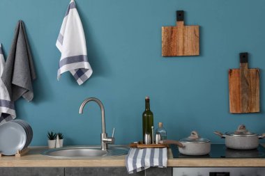 Gri tezgahları, kesme tahtaları ve elektrikli sobası olan modern mutfağın içi.