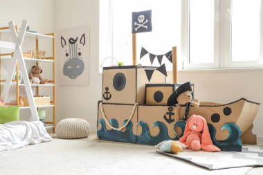 Çocuk odasında oyuncakları olan korsan karton gemi.