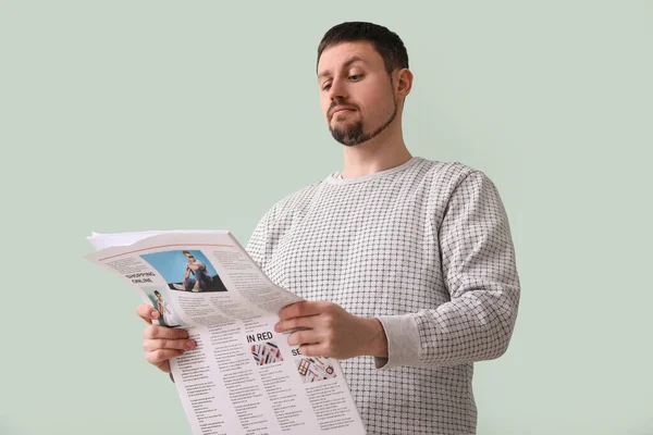 Handsome man reading newspaper on green background