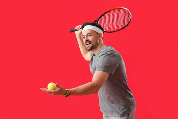 Sportlicher Junger Mann Mit Tennisschläger Und Ball Auf Rotem Hintergrund — Stockfoto