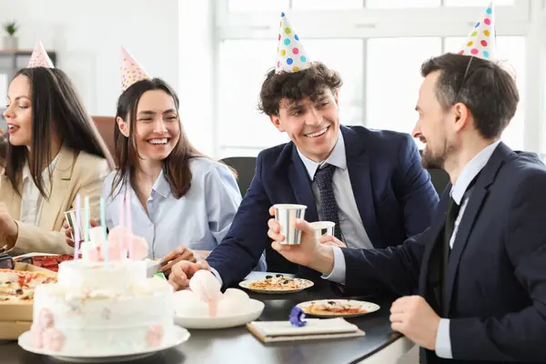 Group of business people drinking at birthday party in office